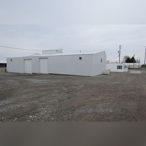 This 34â??x98â?? building includes a 34â??x45â?? shop area with overhead storage, concrete floor, Reznor natural-gas heating unit, 14â??x15â?? overhead door, and walk-in door.  The remaining 34â??x53â?? area has a concrete floor, (3) 10.5â??x14â?? overhead doors, 9â?? slider, (2) walk-in doors, and 220 amp single-phase electric.