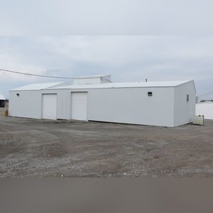 This 34â??x98â?? building includes a 34â??x45â?? shop area with overhead storage, concrete floor, Reznor natural-gas heating unit, 14â??x15â?? overhead door, and walk-in door.  The remaining 34â??x53â?? area has a concrete floor, (3) 10.5â??x14â?? overhead doors, 9â?? slider, (2) walk-in doors, and 220 amp single-phase electric.