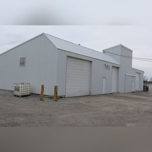 This 34â??x98â?? building includes a 34â??x45â?? shop area with overhead storage, concrete floor, Reznor natural-gas heating unit, 14â??x15â?? overhead door, and walk-in door.  The remaining 34â??x53â?? area has a concrete floor, (3) 10.5â??x14â?? overhead doors, 9â?? slider, (2) walk-in doors, and 220 amp single-phase electric.