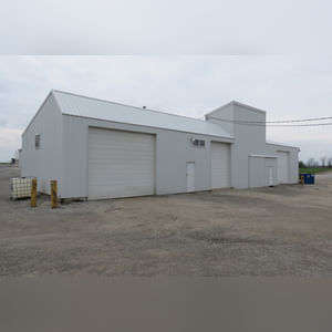 This 34â??x98â?? building includes a 34â??x45â?? shop area with overhead storage, concrete floor, Reznor natural-gas heating unit, 14â??x15â?? overhead door, and walk-in door.  The remaining 34â??x53â?? area has a concrete floor, (3) 10.5â??x14â?? overhead doors, 9â?? slider, (2) walk-in doors, and 220 amp single-phase electric.