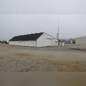 This drive-thru storage building is 60â??x105â?? with concrete floors, a front office area, a newer shingled roof, and 480 amp service.  There are (8) 11â??x32â?? individual storage bays, (2) end-sliders, and (2) walk-in doors.